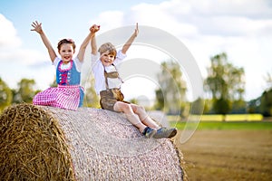 Two kids, boy and girl in traditional Bavarian costumes in wheat field