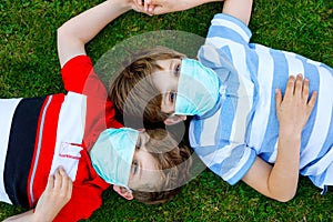 Two kids boys in medical mask as protection against pandemic coronavirus disease. Children, lovely siblings and best