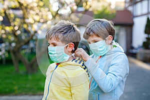 Two kids boys in medical mask as protection against pandemic coronavirus disease. Children, lovely siblings and best