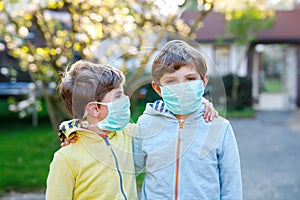 Two kids boys in medical mask as protection against pandemic coronavirus disease. Children, lovely siblings and best