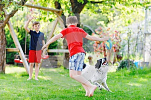 Two kids boys playing with family dog in garden. Laughing children, adorable siblings having fun with dog, with running