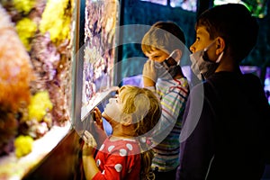 Two kids boys and toddler girl visiting together zoo aquarium. Three children watching fishes and jellyfishes. School