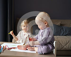 Two kids brother and sister drawing and playing together at home