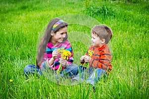 Two kids with dandelions on a meadow