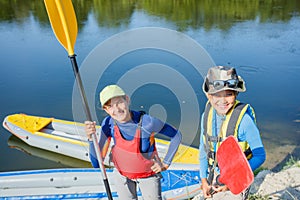 Two kids enjoying kayak ride on beautiful river. Little boy and teenager girl kayaking on hot summer day. Water sport