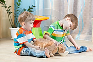 two kids feeding cat indoors