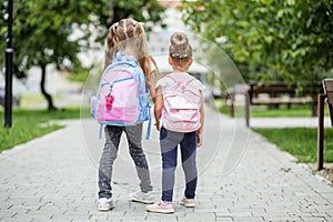 Two kids go to school with backpacks. The concept of school, study, education, friendship, childhood.