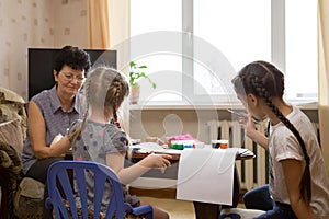 Two kids and grandmother painting at home