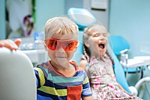 Two kids having fun and wearing medical eyeglasses during visit to dentist office