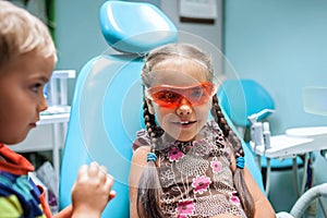 Two kids having fun and wearing medical eyeglasses during visit to dentist office