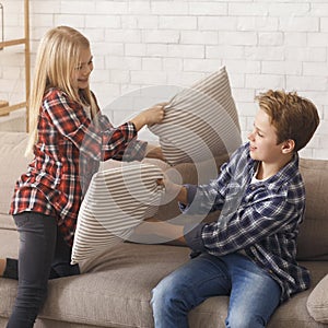 Two Kids Having Pillow Fight Playing On Couch Indoor
