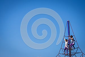 Two kids high up on jungle gym at the playground