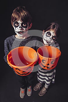 Two kids holding pumpkin buckets at Halloween