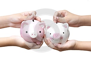 Two kids holding and putting coins into piggy banks