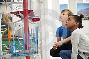 Two kids kneeling and looking at a science exhibit photo