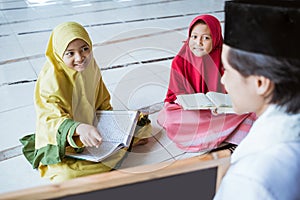 two kids learning to read quran and point to black board with muslim teacher or ustad