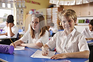 Two kids in a lesson at a primary school look to camera