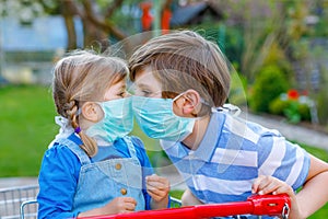 Two kids, little toddler girl and school boy in medical mask as protection against pandemic coronavirus disease