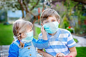 Two kids, little toddler girl and school boy in medical mask as protection against pandemic coronavirus disease