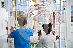 Two kids looking at a science exhibit, back view