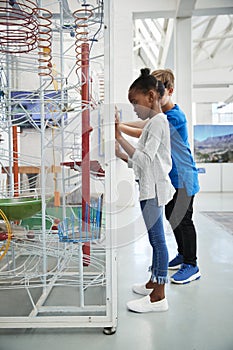 Two kids and looking at a science exhibit, vertical photo