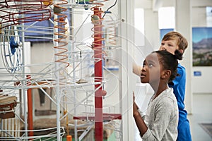 Two kids looking at a science exhibit, waist up