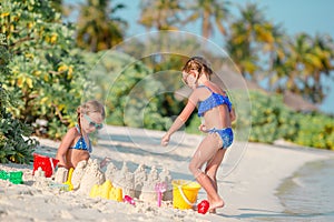 Two kids making sand castle and having fun at tropical beach