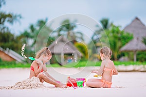 Two kids making sand castle and having fun at tropical beach