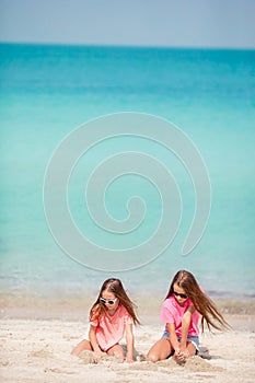 Two kids making sand castle and having fun at tropical beach