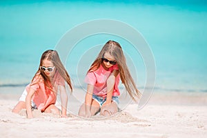 Two kids making sand castle and having fun at tropical beach