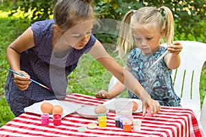 Two kids painting Easter eggs outdoors