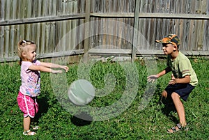 Two kids playing ball in a backyard