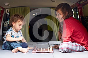 Two kids playing chess in a camper van