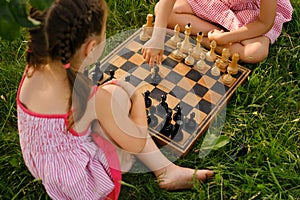 Two kids are playing chess on an old wooden chessboard