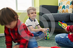 Two kids playing construction blocks sitting on floor at home