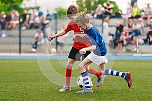 Two Kids Playing Football Ball on Grass Field. Happy School Boys Kicking Ball During Tournament Game