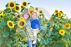 Two kids playing in a sunflower field on sunny day