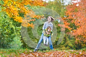 Two kids playing togeter in autumn park