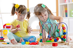 Two kids playing with wooden blocks in their room