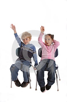 Two kids raising their hands in school