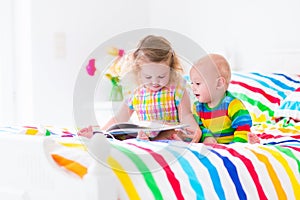 Two kids reading a book in bed