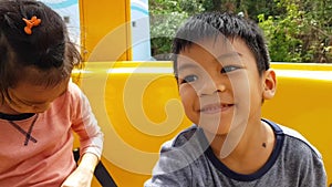 Two Kids riding on yellow ferris wheel in amusement park