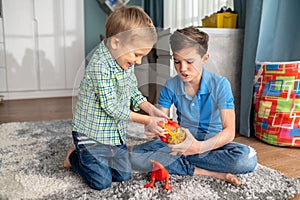 Two kids with rubber animal figures sitting in a room