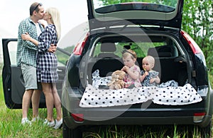 Two kids sit in a car luggage carrier.