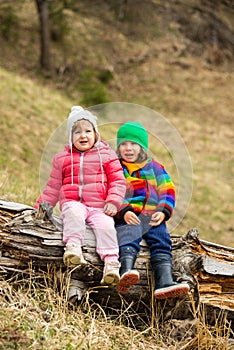 Two kids sitting on tree trunk