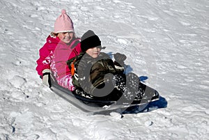 Two kids on a snow sled.