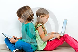 Two kids socializing with laptop and tablet. photo