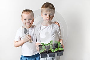 Two kids with sprouts and gardening tools, ecology and environment theme on white background