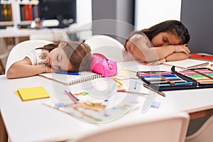 Two kids students sitting on table sleeping at classroom