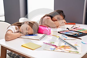 Two kids students sitting on table sleeping at classroom